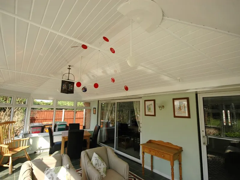A conservatory with an insulated ceiling fitted, furnished and in use on a sunny day